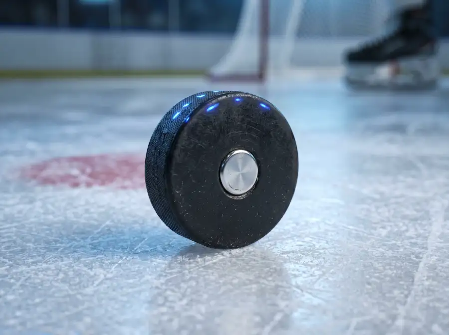 Disco oficial de hockey NHL con sensor integrado sobre la pista, ilustrando el sistema de tracking a 100 Hz